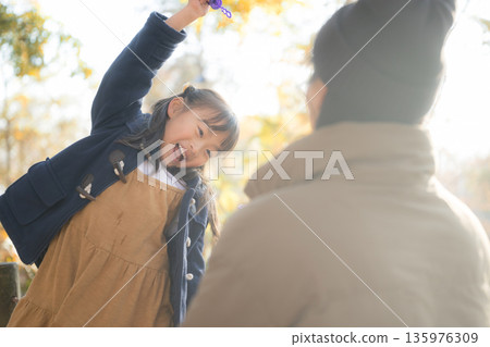 秋日公園裡，一個快樂的女孩在逆光下微笑玩耍。 135976309