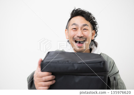 面帶微笑的送餐員手提外帶袋，準備送餐，這是送餐服務的工作畫面。 135976620