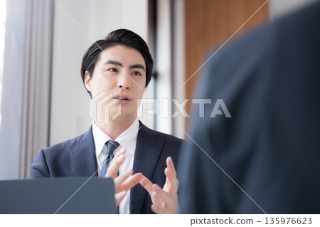 A man in a suit conducting business negotiations and planning at a company, a businessman having a meeting 135976623