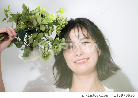 手捧一束新鮮綠植的春日美照。適合婚紗照和保養品拍攝的唯美照片。看向鏡頭。 手捧一束新鮮綠植的春日美照。適合婚紗照和保養品拍攝的唯美照片。看向鏡頭。 135976636