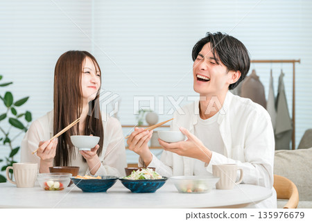 一對年輕的亞洲夫婦正在家裡的餐桌上享用美食。 135976679
