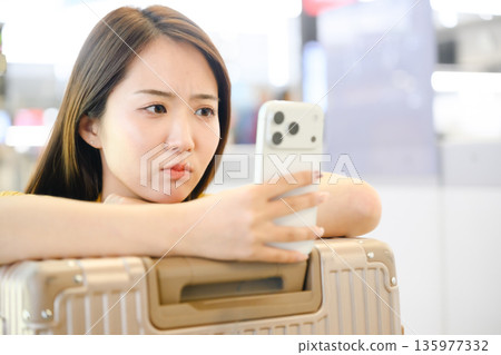 一名女子在機場查看她的智慧型手機。照片由關西國際機場(KIX)提供。 一名女子在機場查看她的智慧型手機。照片由關西國際機場(KIX)提供。 135977332