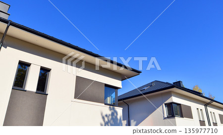 Terraced family homes in newly developed housing estate. The real estate market in the suburbs. New single family houses in a new development area. Residential homes with modern facade. 135977710