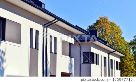 Terraced family homes in newly developed housing estate. The real estate market in the suburbs. New single family houses in a new development area. Residential homes with modern facade. 135977713