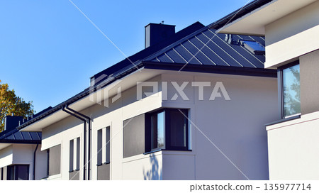 Terraced family homes in newly developed housing estate. The real estate market in the suburbs. New single family houses in a new development area. Residential homes with modern facade. 135977714