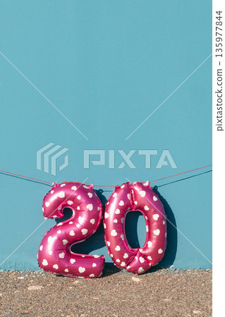 pink number 20 balloons against a vivid blue wall 135977844