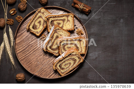Pieces of homemade strudel with walnuts in a wooden tray 135978639