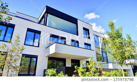 Modern architecture of urban residential apartment buildings on a sunny day. Low-rise apartment buildings with large windows and extensive terraces. White facade of a modern apartment building. Modern architecture of urban residential apartment buildings on a sunny day. Low-rise apartment buildings with large windows and extensive terraces. White facade of a modern apartment building. 135978796
