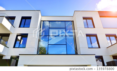 Modern architecture of urban residential apartment buildings on a sunny day. Low-rise apartment buildings with large windows and extensive terraces. White facade of a modern apartment building. Modern architecture of urban residential apartment buildings on a sunny day. Low-rise apartment buildings with large windows and extensive terraces. White facade of a modern apartment building. 135978800