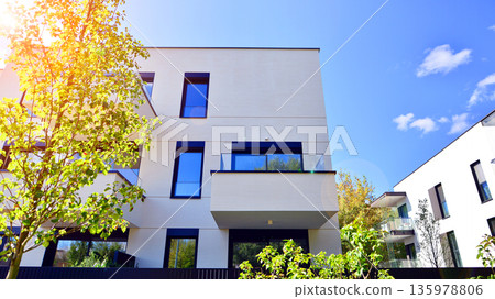 Modern architecture of urban residential apartment buildings on a sunny day. Low-rise apartment buildings with large windows and extensive terraces. White facade of a modern apartment building. Modern architecture of urban residential apartment buildings on a sunny day. Low-rise apartment buildings with large windows and extensive terraces. White facade of a modern apartment building. 135978806