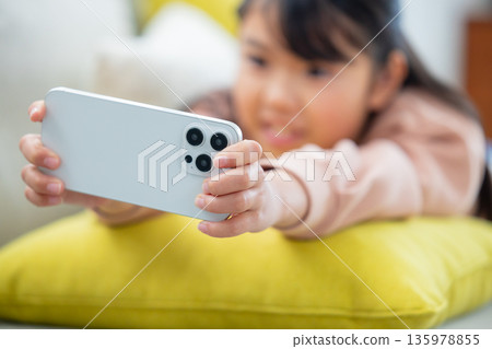 玩智慧型手機的小學生女孩 135978855