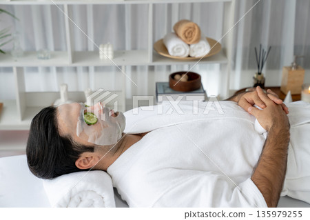 Man customer indulges in rejuvenating with cucumber facial care. Quiescent Man customer indulges in rejuvenating with cucumber facial care. Quiescent 135979255