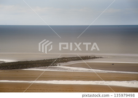 Calm Beach Scene With Jetty, Wide Horizon, Soft Sand, And Subtle Sea Mist Calm Beach Scene With Jetty, Wide Horizon, Soft Sand, And Subtle Sea Mist 135979498
