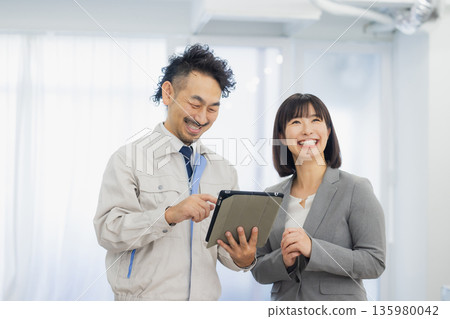 一位女商人和一個工人面露不滿地看著空調。 135980042