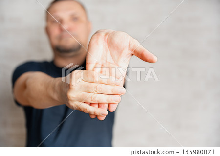 Man doing therapeutic exercises, streching his wrist Man doing therapeutic exercises, streching his wrist 135980071
