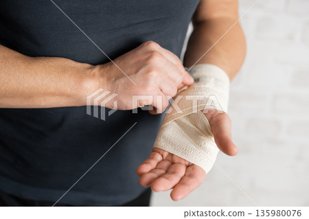 Man's hand wrapping elastic bandage Man's hand wrapping elastic bandage 135980076