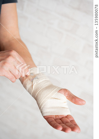 Man's hand wrapping elastic bandage 135980078