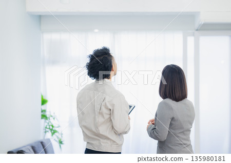 一位女商人和一個工人面露不滿地看著空調。 135980181