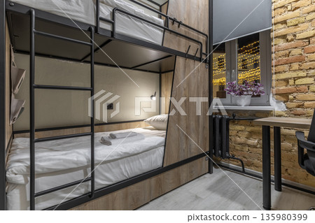 Cozy night view of a loft hostel bunk bed and festive city window Cozy night view of a loft hostel bunk bed and festive city window 135980399