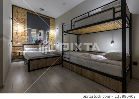 Modern loft hostel room with double bed and wooden bunk beds at night Modern loft hostel room with double bed and wooden bunk beds at night 135980402