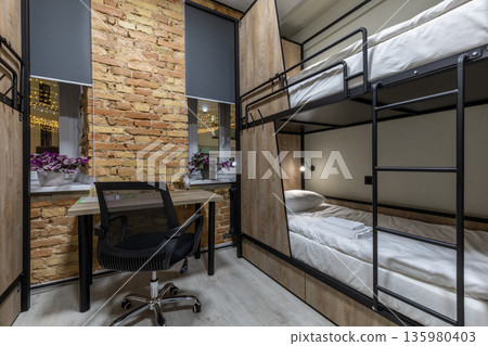 Loft hostel dormitory with workspace and wooden bunk beds at night Loft hostel dormitory with workspace and wooden bunk beds at night 135980403