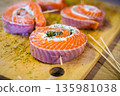 Cooked salmon rolls with creamy filling and herbs on a wooden board. Elegant seafood appetizer perfect for healthy cuisine, festive table, or restaurant presentation 135981038