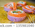 Cooked salmon rolls with creamy filling and herbs on a wooden board. Elegant seafood appetizer perfect for healthy cuisine, festive table, or restaurant presentation 135981040