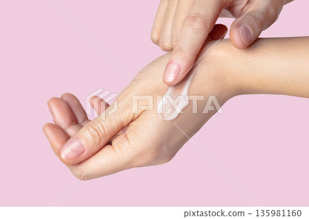 Woman hands with a swatch sampled with a smear of cream. Self-care concept, skin care, hand care, facial care. Isolated pink background photo close up 135981160