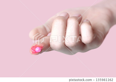 A drop of capsule pink cream on the finger of a woman. Swatch of pink popular Niacinamide Capsule Cream. isolated on pink background photo 135981162