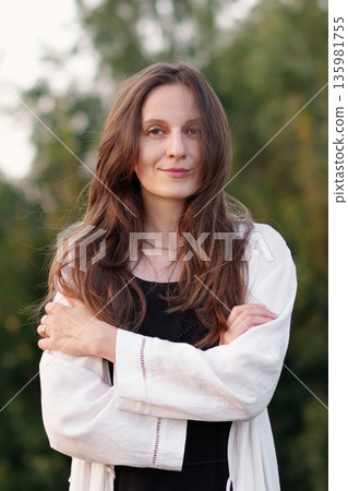 Smiling Confident Brunette Woman With Long, Wavy Hair Crossed Arms Looking at camera, Outdoors in sunlight. Slow motion. Medium Shot. Smiling Confident Brunette Woman With Long, Wavy Hair Crossed Arms Looking at camera, Outdoors in sunlight. Slow motion. Medium Shot. 135981755