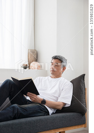 A man reading a book on the sofa 135981829