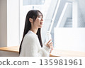 A woman drinking water at the window 135981961