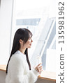 A woman drinking water at the window 135981962