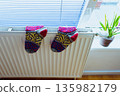 Woolen socks dry on radiator on cold winter day. 135982179