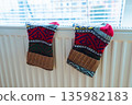 Woolen socks dry on radiator on cold winter day. 135982183