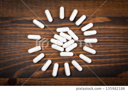 White Medical Capsules Arranged In Circular Pattern On Wooden Background White Medical Capsules Arranged In Circular Pattern On Wooden Background 135982186