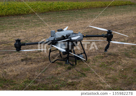 Industrial agricultural drone with multiple rotors resting on a dry field for aerial surveying and crop monitoring 135982278