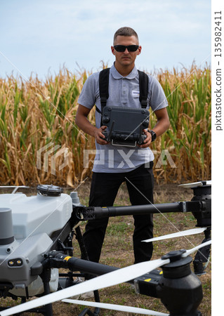 Drone pilot in a cornfield with remote controller and drone equipment for agricultural fieldwork 135982411