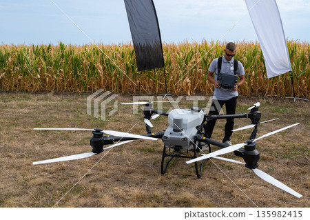 Drone operator tests aerial drone in a cornfield with banners and equipment in open field Drone operator tests aerial drone in a cornfield with banners and equipment in open field 135982415