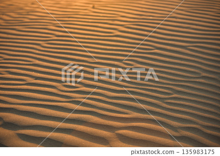 Abstract close-up of sand ripples on a beach in Vlora, Albania, captured on August 2025. Warm sunset light creates soft golden highlights and contrasting shadows, forming natural patterns Abstract close-up of sand ripples on a beach in Vlora, Albania, captured on August 2025. Warm sunset light creates soft golden highlights and contrasting shadows, forming natural patterns 135983175