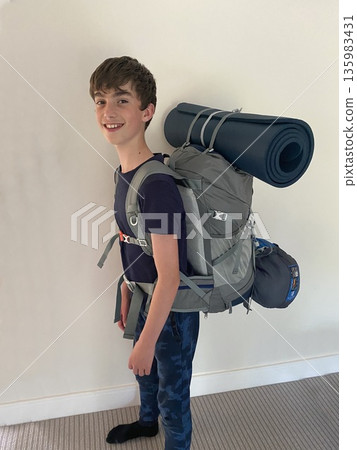 Smiling boy ready for hiking with backpack, sleeping pad and sleeping bag on his back Smiling boy ready for hiking with backpack, sleeping pad and sleeping bag on his back 135983431