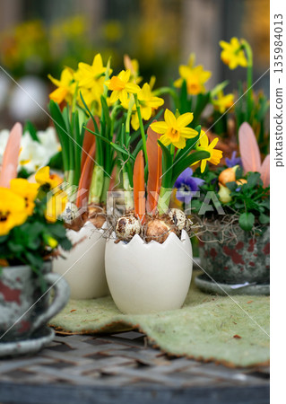 View of an eggshell-shaped flower pot with yellow daffodil flowers. 135984013