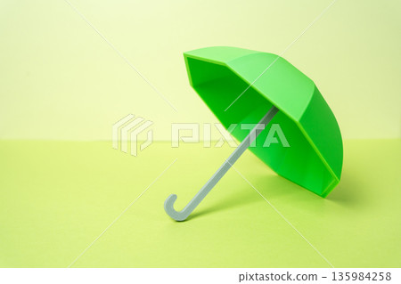 Green Umbrella. Business, life, and health insurance. Security and protection. Risk management concept, stability and confidence. Financial safeguards for companies, families and personal wellbeing 135984258