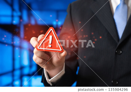 A businessman warns of something unacceptable by holding a sign of attention. Red flags for a business leader. A serious breakdown, accident, or error. Crisis alert, risk prevention A businessman warns of something unacceptable by holding a sign of attention. Red flags for a business leader. A serious breakdown, accident, or error. Crisis alert, risk prevention 135984296