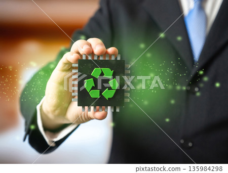 A businessman holds a computer microchip with a recycling symbol in his hand. Recycling of electronic waste. Extraction of valuable metals. Preventing harmful impact of electronic waste on environment A businessman holds a computer microchip with a recycling symbol in his hand. Recycling of electronic waste. Extraction of valuable metals. Preventing harmful impact of electronic waste on environment 135984298