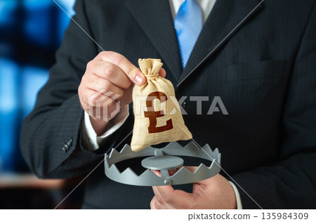 A businessman is holding the British pound in a trap. A financial trap, risk of fraud. High debts, unfavorable loan terms. Budget problems. Credit pressure warning, financial literacy A businessman is holding the British pound in a trap. A financial trap, risk of fraud. High debts, unfavorable loan terms. Budget problems. Credit pressure warning, financial literacy 135984309