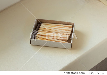 New match box full of wooden matches. matches on the windowsill. Everyday utility item for sparking fire. New match box full of wooden matches. matches on the windowsill. Everyday utility item for sparking fire. 135985132