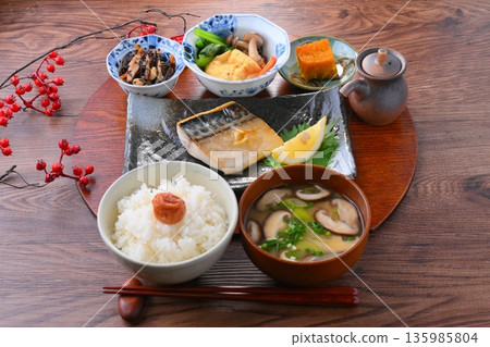 A Japanese meal consisting of one soup and three side dishes: rice, miso soup, a side dish, a side dish, grilled salted mackerel, grilled fish, and rice with pickled plums. A Japanese meal consisting of one soup and three side dishes: rice, miso soup, a side dish, a side dish, grilled salted mackerel, grilled fish, and rice with pickled plums. 135985804