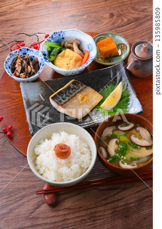 日式餐點,包括一份湯和三道小菜:米飯、味噌湯、一道小菜、一道小菜、烤鹹鯖魚、烤魚和梅子飯。 日式餐點,包括一份湯和三道小菜:米飯、味噌湯、一道小菜、一道小菜、烤鹹鯖魚、烤魚和梅子飯。 135985809