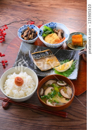 日式餐點,包括一份湯和三道小菜:米飯、味噌湯、一道小菜、一道小菜、烤鹹鯖魚、烤魚和梅子飯。 日式餐點,包括一份湯和三道小菜:米飯、味噌湯、一道小菜、一道小菜、烤鹹鯖魚、烤魚和梅子飯。 135985810